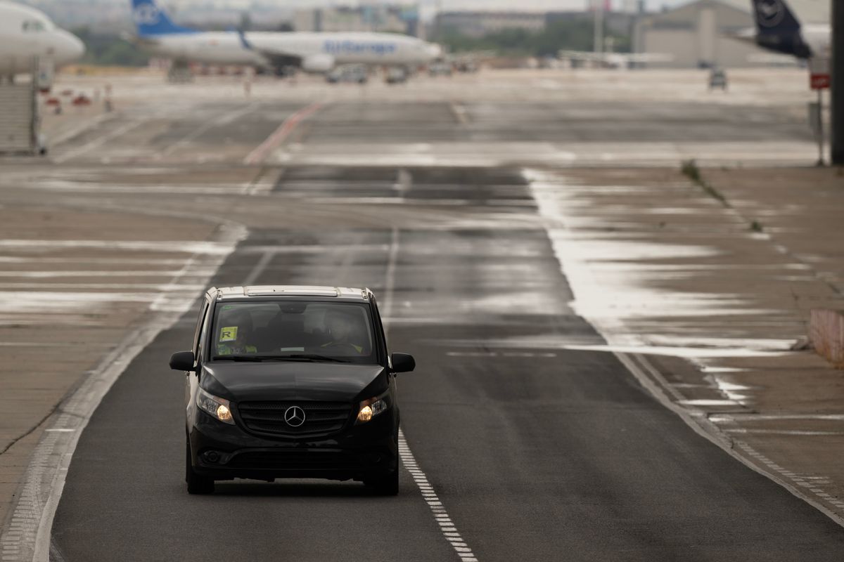 A chauffeur waiting beside a vehicle for arriving guests