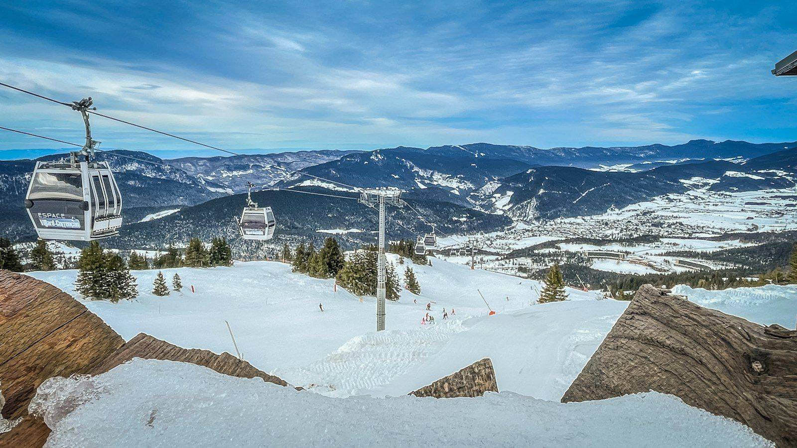 Gondola lifts climbing a snowy slope above an Alpine village